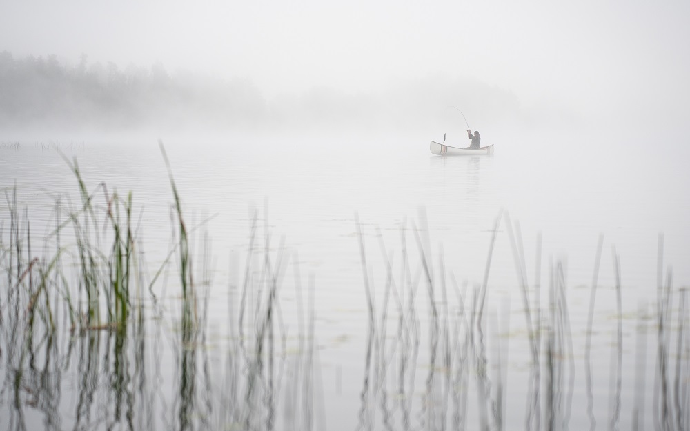 person with fish on hook on foggy morning