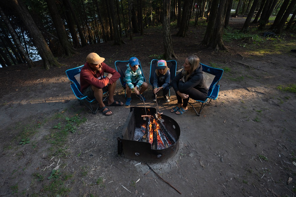 Family cooking spider dogs around a campfir