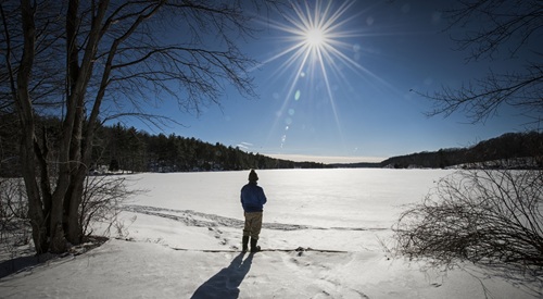 randonneur debout au bord d'un lac enneigé