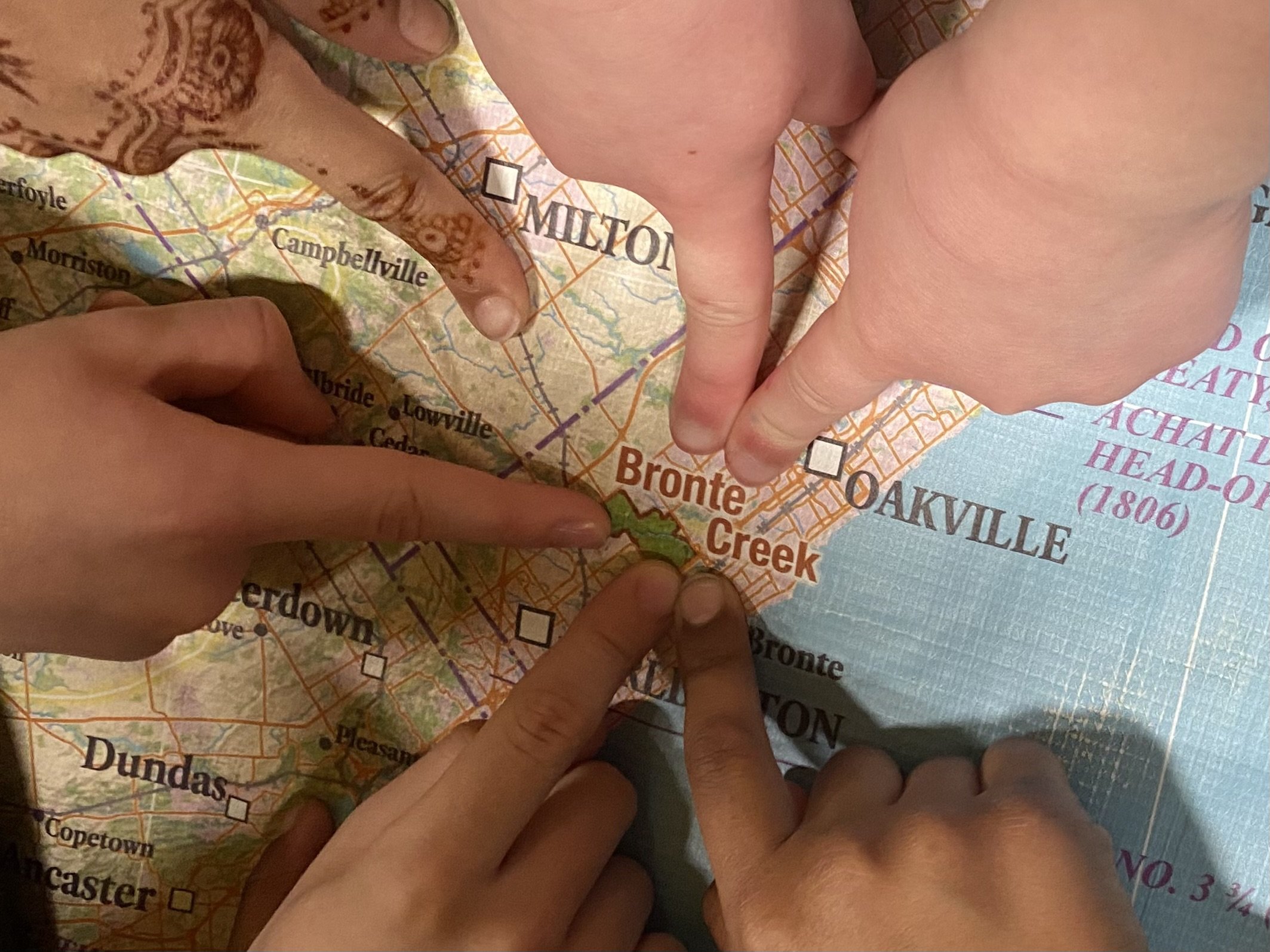 Many fingers pointing to Bronte Creek Provincial Park on a map.