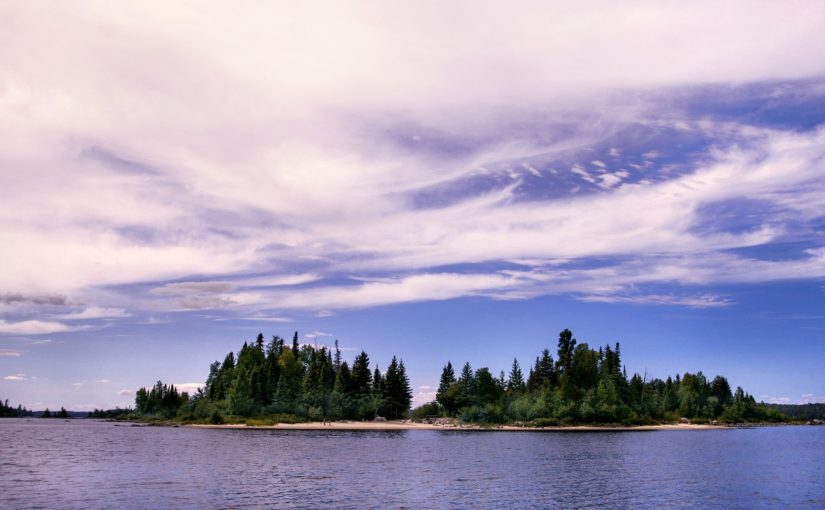 Île couverte de conifères sous un ciel bleu vaporeux.