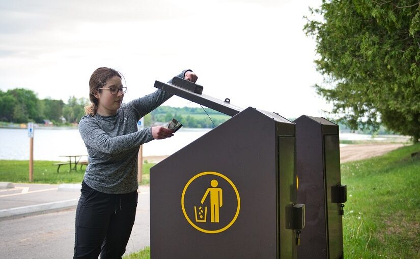 Une visiteuse jetant des déchets au parc provincial Emily.