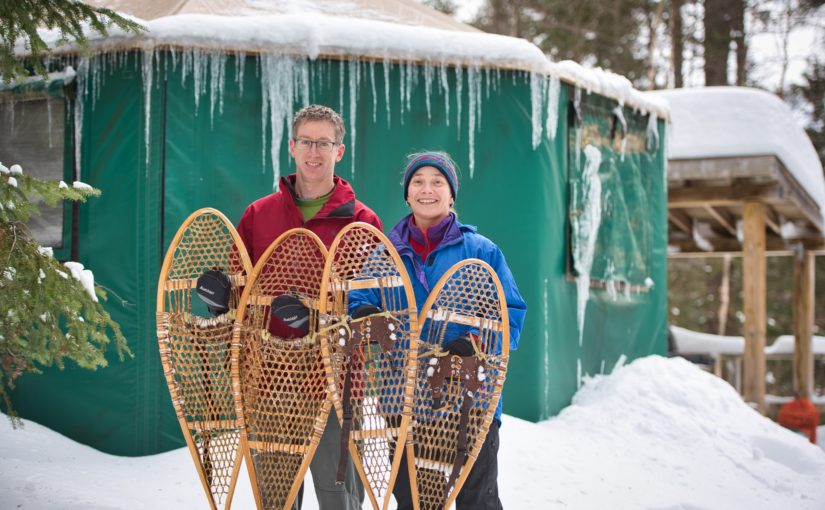 A couple with their snowshoes outside a yurt