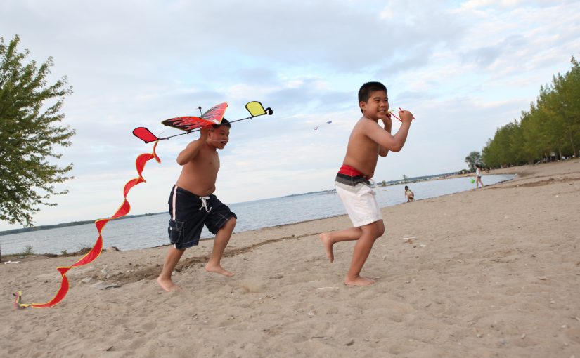 two children running on beach with kite