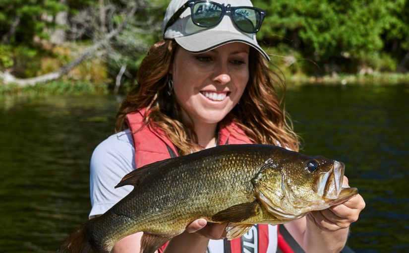 Woman with a white cap holding up a Largemouth Bass