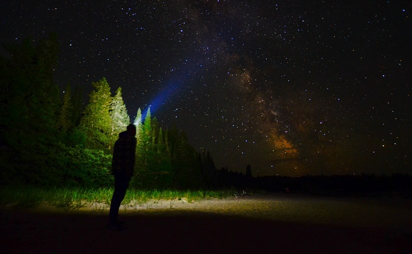 Man with headlamp looks up at stars